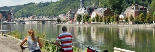 Fietsers langs rivier in stadslandschap.