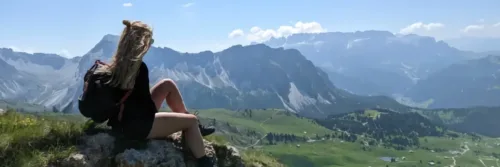 Vrouw zittend op rots met bergzicht.