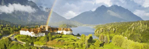Regenboog boven hotel aan meer en bergen